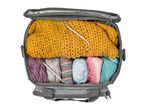 Grey knitting bag filled with colorful yarn, knitted items, and circular knitting needles.