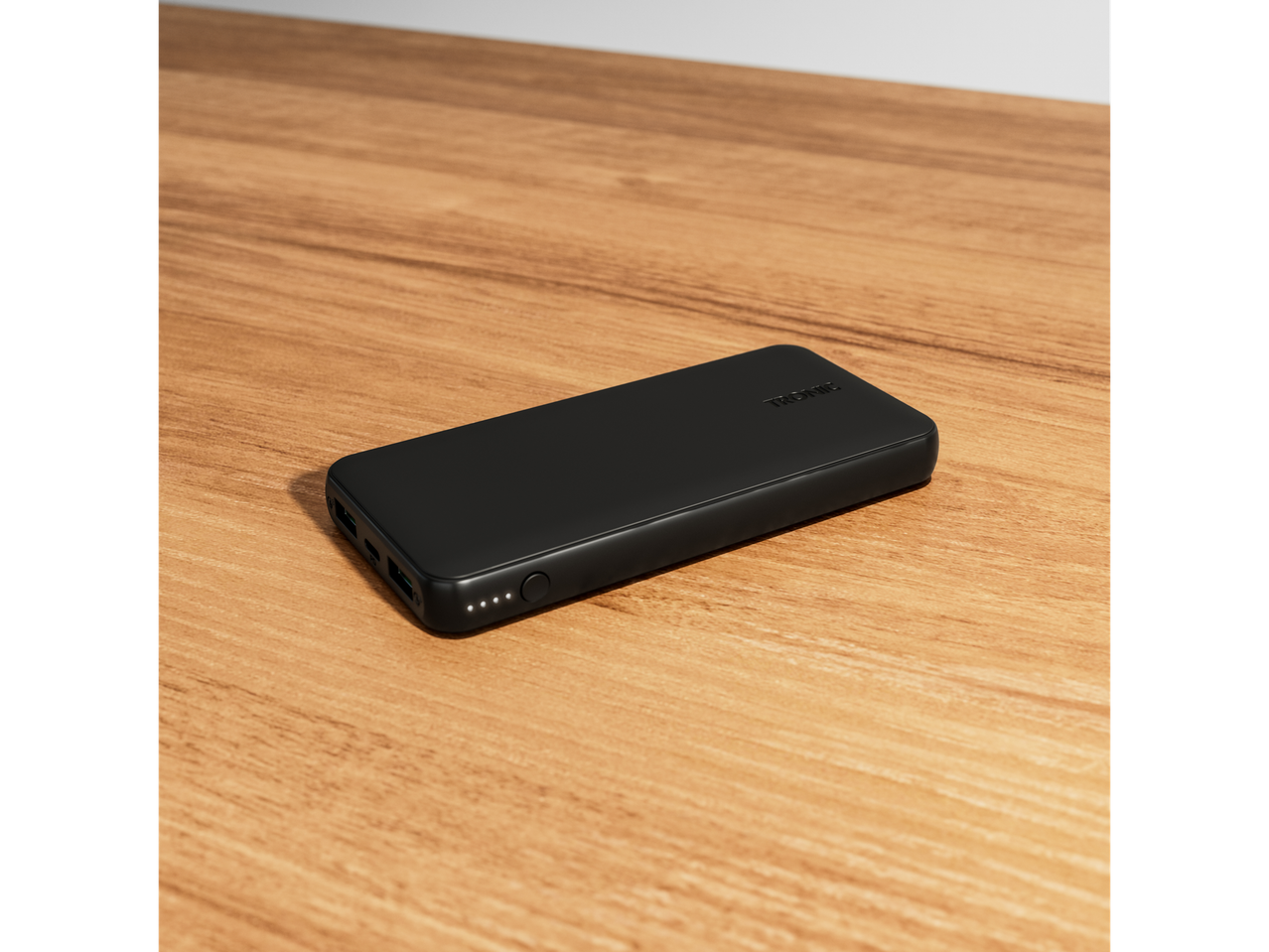 A black Trovic power bank sits on a wooden table.