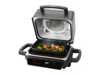 Open electric grill with vegetables cooking, showing heating element and digital display.