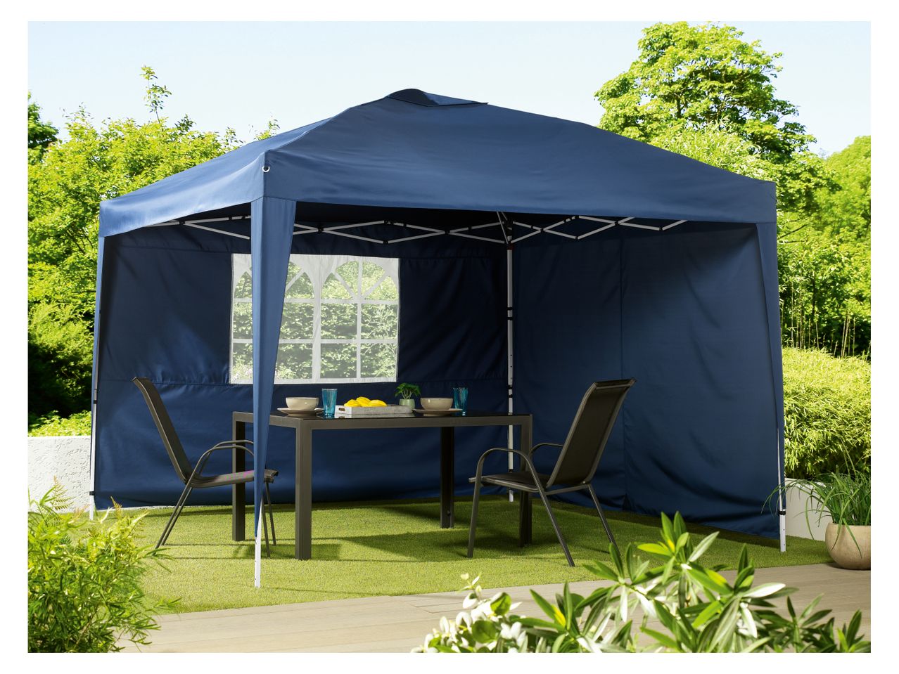 A navy blue pop-up gazebo with side panels provides shade for an outdoor patio table and chairs.