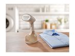 Handheld garment steamer next to a folded light blue shirt on a wooden table.