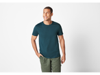 Homem sorridente vestindo uma camiseta verde-escura e calças verdes.