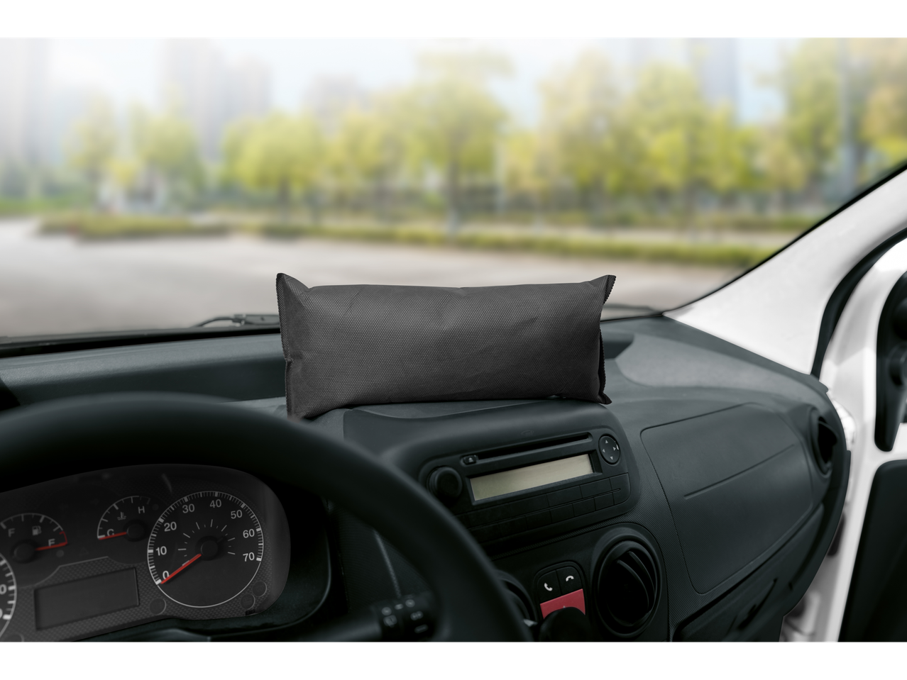 Juoda pagalvėlė ant automobilio prietaisų skydelio su neryškiu fonu