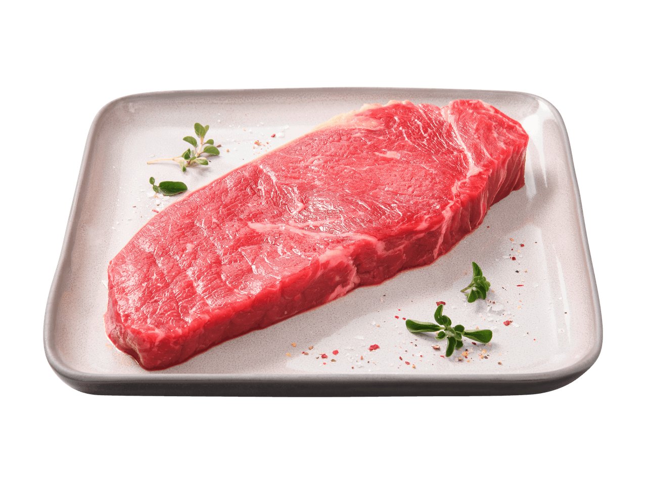 Bistecca di manzo cruda su un piatto con erbe aromatiche e spezie.