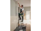 Painter painting a wall from a ladder, paint bucket.