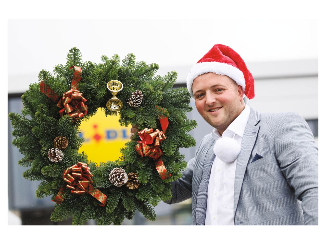 Christmas wreath and man in suit wearing a Santa hat.