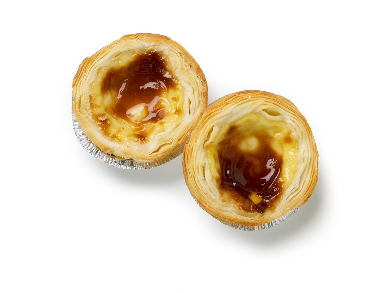 Deux Pastel de Nata dorés avec des dessus caramélisés dans des moules en aluminium.