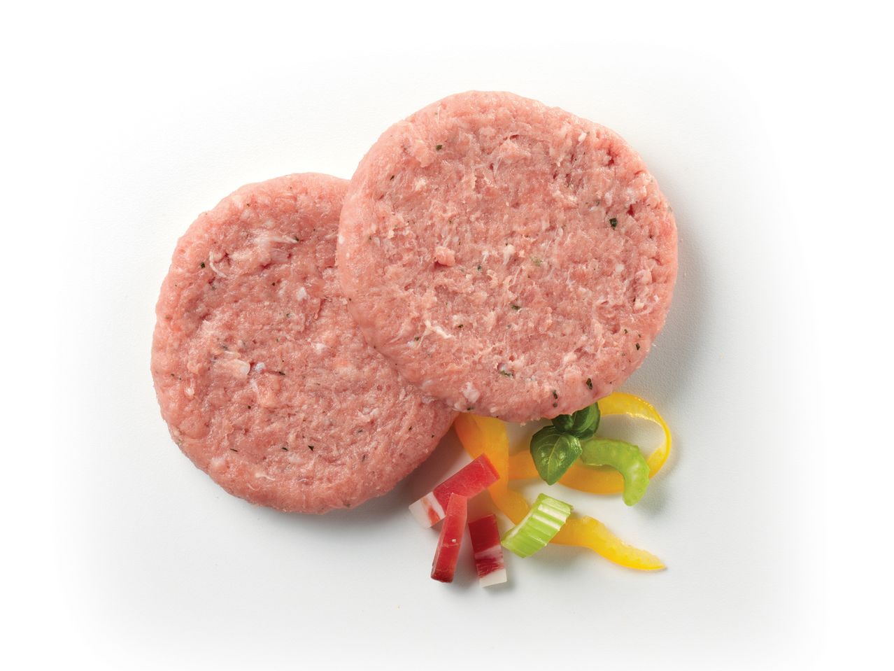 Due Hamburger con tacchino e speck crudi pronti per la cottura, accanto a verdure fresche.