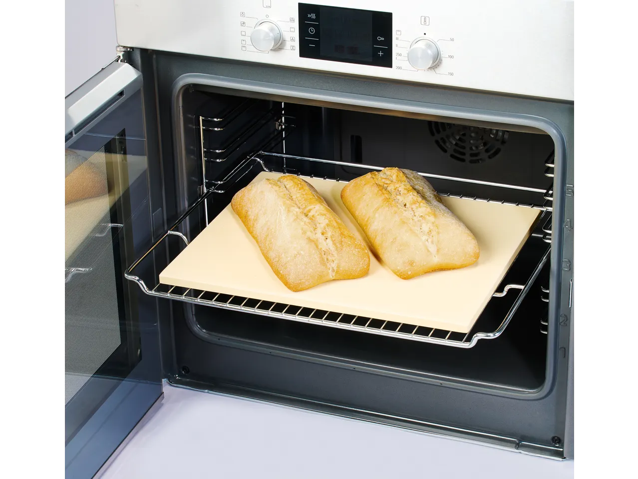 Freshly baked bread on a baking stone inside an open oven