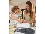 A woman and child bake using a small, gray electric Food dehydrator. 