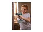 Woman in safety glasses drilling into wood with a cordless drill, sawdust flying.