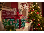 Crelando wrapping paper with Christmas designs and red ribbons, next to a Christmas tree.