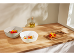 Two Joseph Joseph bowls filled with cherry tomatoes sit on a kitchen counter.