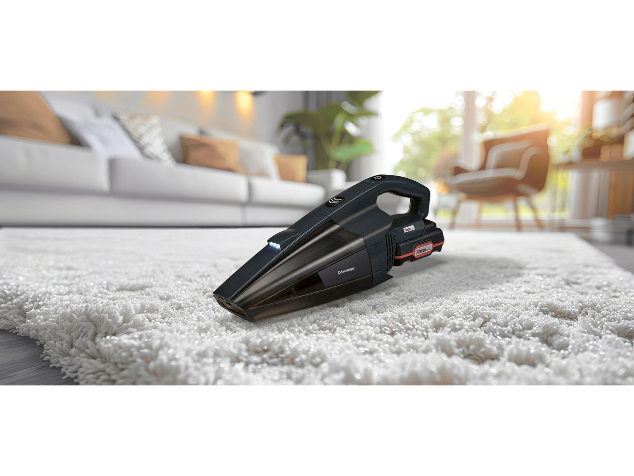 A black handheld vacuum cleaner sits on a fluffy white rug in a living room.