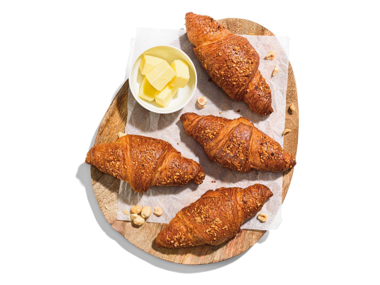 Mogyorós croissant-ok és vaj fa deszkán.