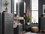 A modern bathroom with dark gray cabinets, a light beige sink, and a large window with blinds.