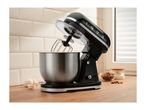 Black stand mixer with a stainless steel bowl on a wooden countertop