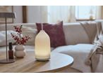 A glowing aroma diffuser emitting mist on a wooden table, with a sofa in the background.