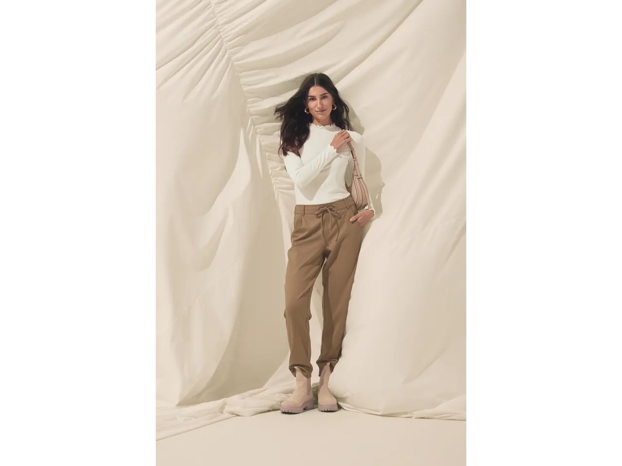 Femeie în bluză albă Esmara cu mânecă lungă și pantaloni maro.