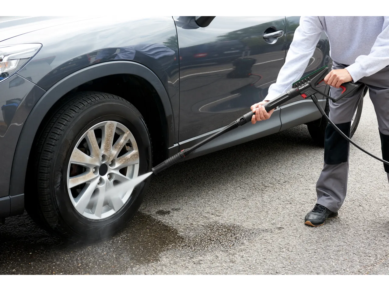 A person cleans a car with a Parkside® pressure washer.