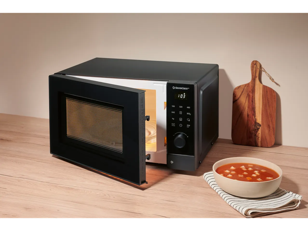 SilverCrest microwave with open door and soup on a wooden table