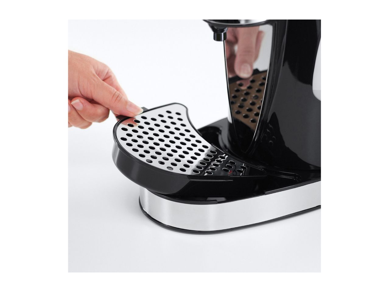 A hand adjusting the drip tray of a black and silver coffee machine.