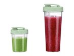 Two clear blender bottles with light green lids, one with green smoothie, one with red smoothie.
