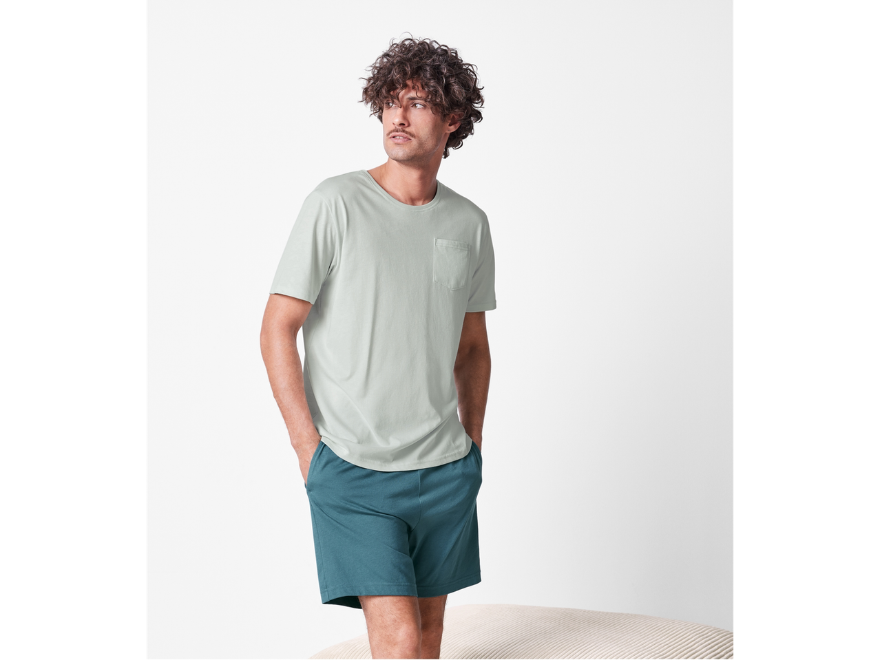 Bărbat cu tricou verde deschis și pantaloni scurți turcoaz.