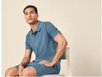 Homem sentado numa cadeira com polo e calções azuis.