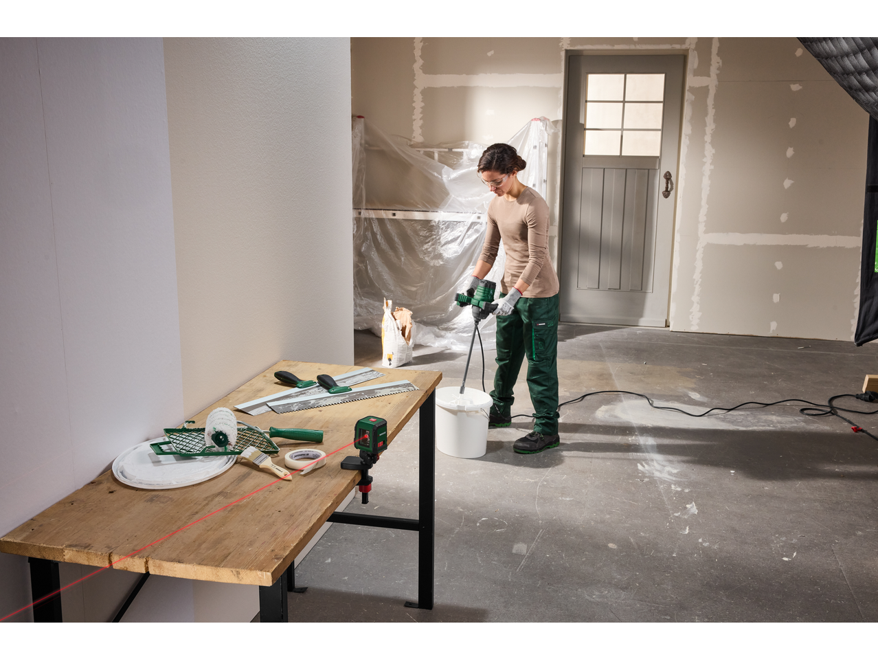 Mulher a misturar material de construção com ferramentas PARKSIDE, incluindo um nível a laser.