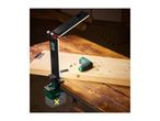 Cordless work light clamped to a wooden workbench next to a small screwdriver.