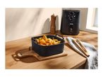 Air fryer with a basket of fried food (fries, onion rings, chicken nuggets) on a wooden board.