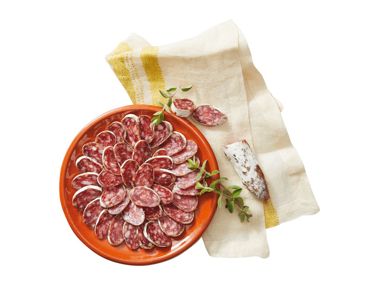 Sliced salami on a terracotta plate with a sprig of oregano, next to a linen napkin.