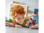 A child playing with a Lego Super Mario kart and figures on a table.