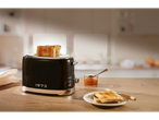 A black toaster with toast, jam, and a plate of toast on a wooden counter.