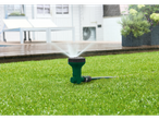 Un irrigatore verde annaffia un prato.