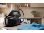 Ferro a vapor SilverCrest preto em tábua de passar com camisa polo azul
