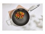 A stir-fry with shrimp and vegetables in a stainless steel pan on a white marble surface.