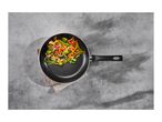 Frying pan with colorful stir-fry vegetables on a grey concrete surface.