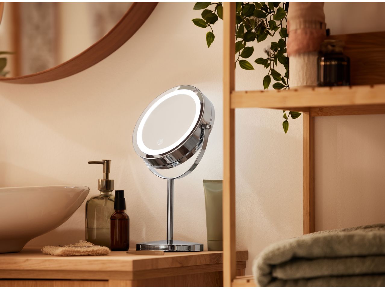 A chrome LED Make-Up Mirror on a wooden counter next to bathroom essentials.
