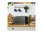 A dark grey microwave on a wooden kitchen counter, surrounded by kitchenware and spices.
