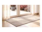 Textured beige doormat with a zen-like raked pattern in front of a glass patio door.