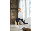 Mulher de t-shirt Crivit branca e leggings escuras a fazer lunges com halteres.
