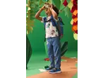 Criança num cenário de selva, com mochila, t-shirt, jeans e sapatilhas, a olhar através de binóculos.