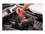 A person connecting a portable jump starter to a car battery.