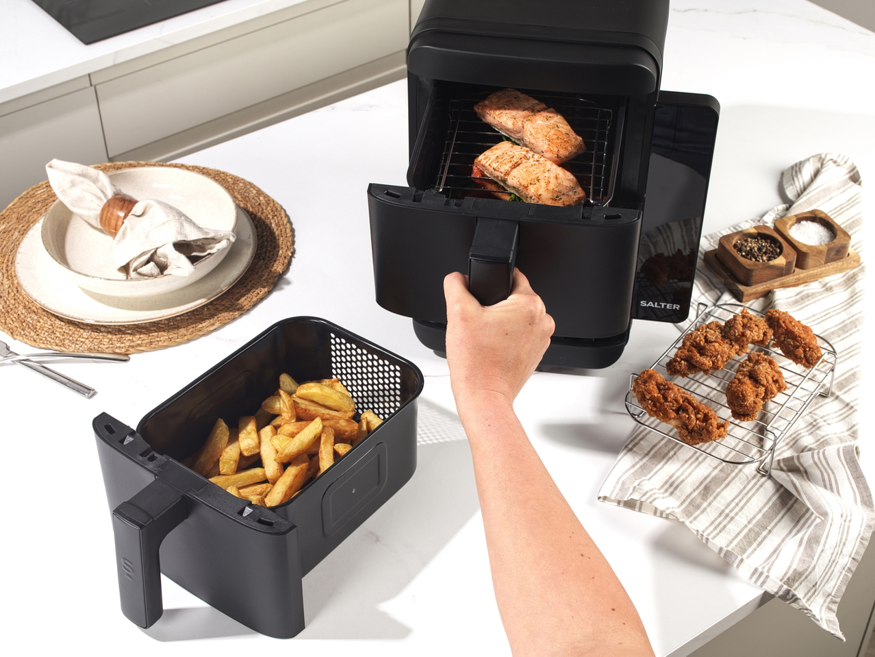 Salter VertiCook Air Fryer 10L cooking salmon, with fries and fried chicken nearby.