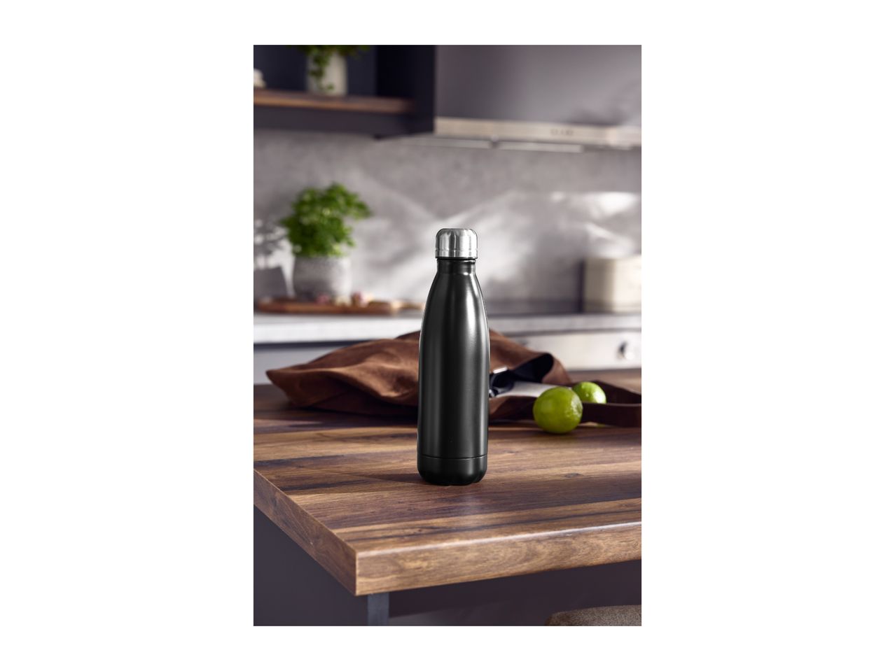 A black stainless steel water bottle on a wooden kitchen table.