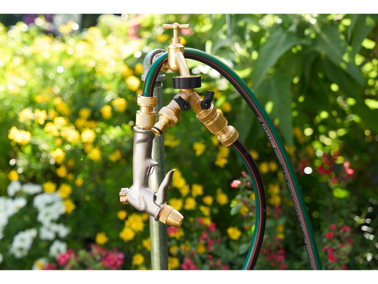 Parkside® baštensko crevo sa pištoljem za prskanje i priključkom za slavinu, na cvetnoj pozadini.