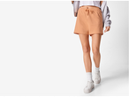 Femeie purtând pantaloni scurți piersici și adidași albi.