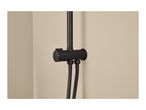 Black shower mixer with a temperature control dial and two flexible hoses against a beige wall.